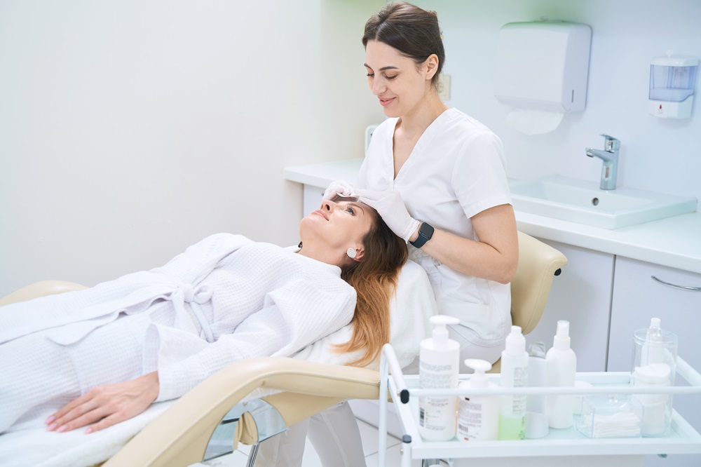 Dermatologist cleans the skin of the patient face with cotton swabs